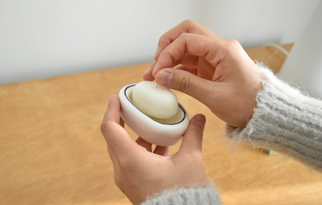Person peeling an egg with a white container on a wooden surface，Honey Flamingo，韓國設計品牌，天然大豆香氛蠟燭