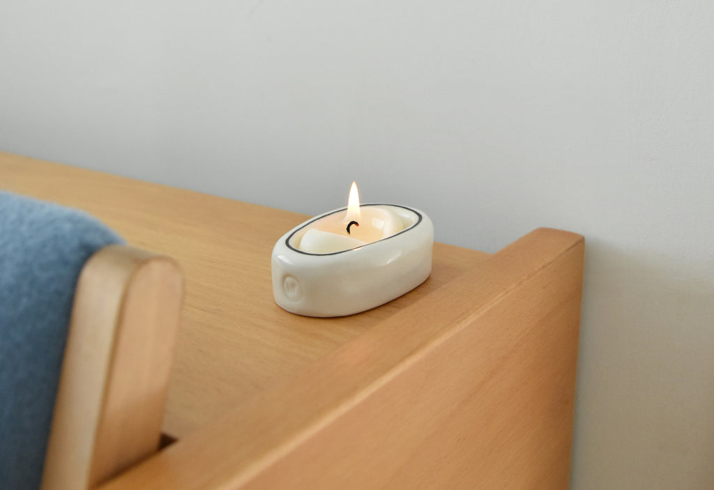 Ceramic candle holder with a lit candle on a wooden surface，Honey Flamingo，韓國設計品牌，天然大豆香氛蠟燭