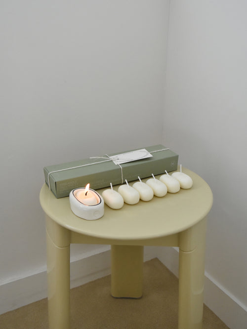 Small round chair with a lit candle, wrapped gift, and small white candles，韓國設計品牌，天然大豆香氛蠟燭