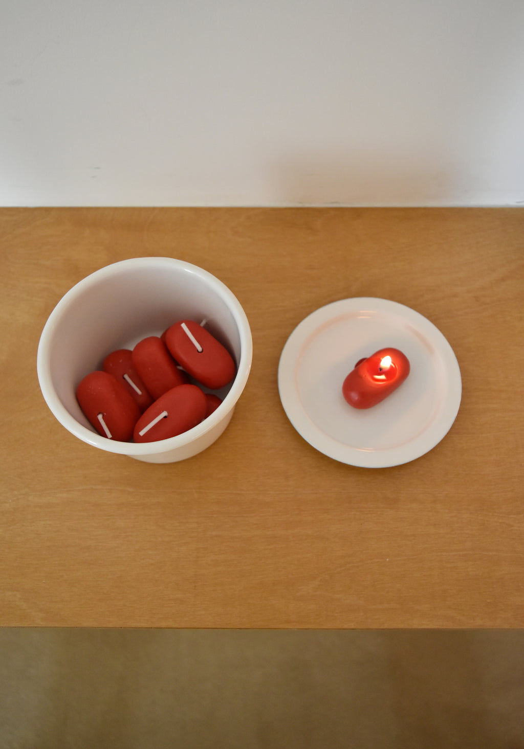 Red candles in a white bowl and on a white plate on a wooden surface，Honey Flamingo，韓國設計品牌，天然大豆香氛蠟燭