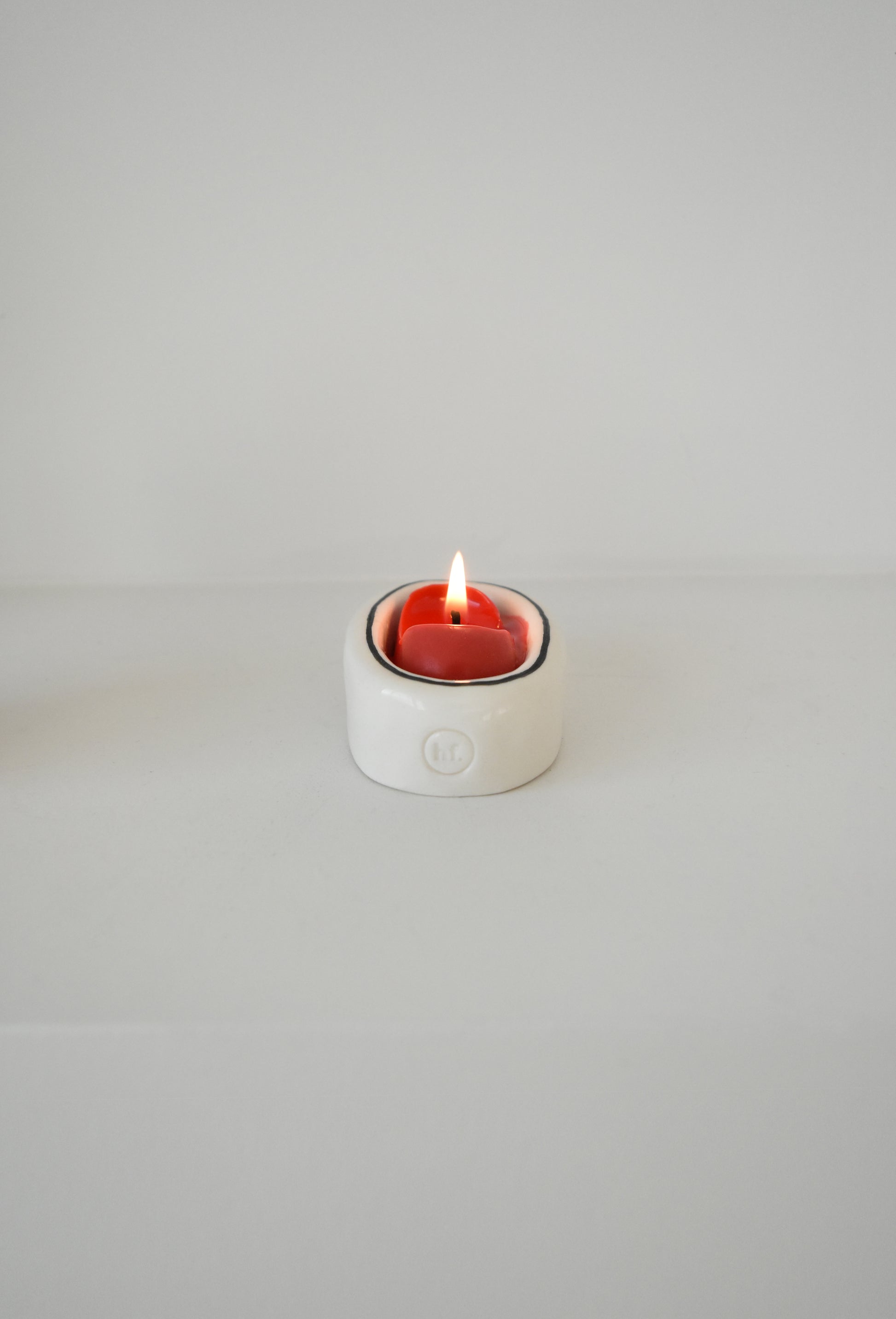Small white candle holder with a lit red candle on a light gray background，Honey Flamingo，韓國設計品牌，天然大豆香氛蠟燭