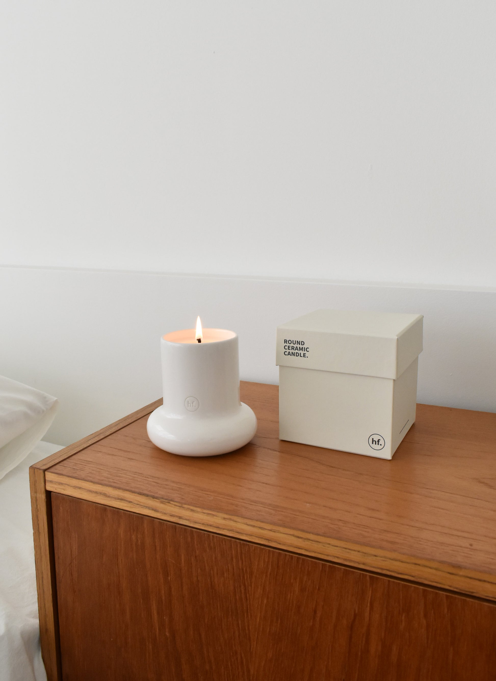 White candle on a wooden surface next to a white box with branding，Honey Flamingo，韓國設計品牌，天然大豆香氛蠟燭