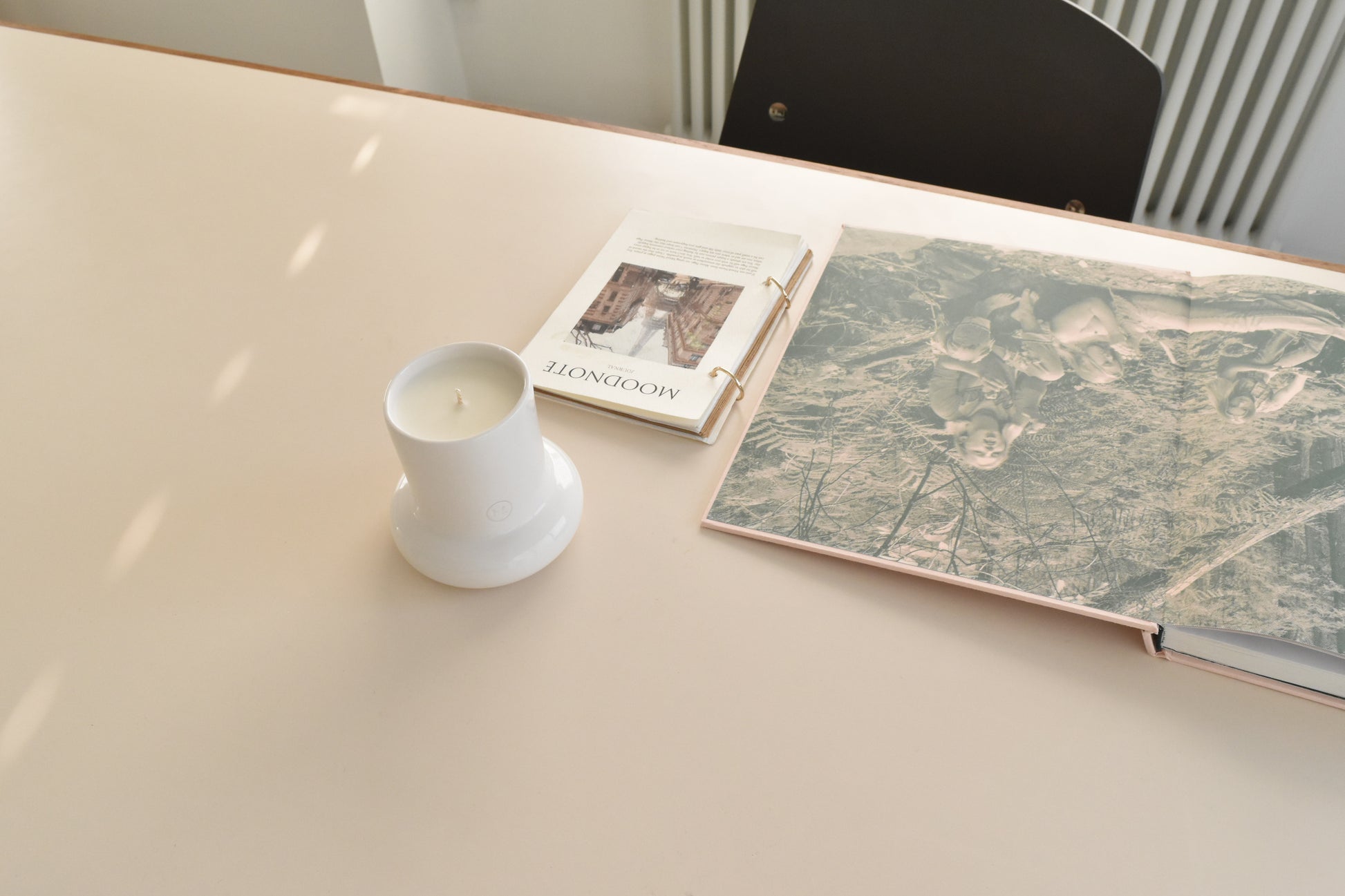 Candle in a white holder on a table next to a book and map，Honey Flamingo，韓國設計品牌，天然大豆香氛蠟燭