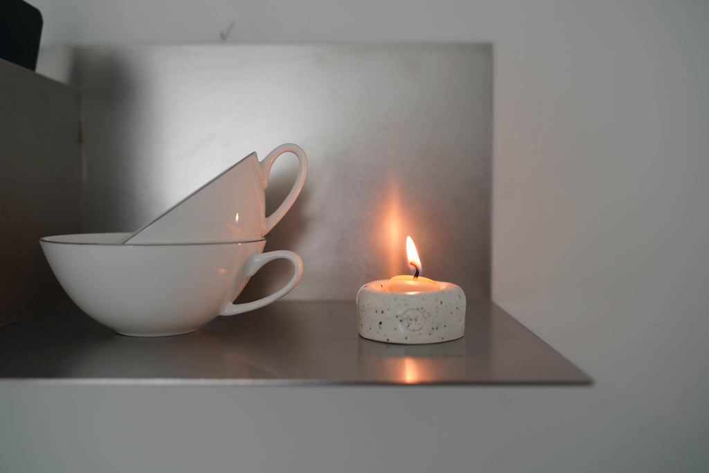 A  small lit Honey Flamingo candle on a metallic surface