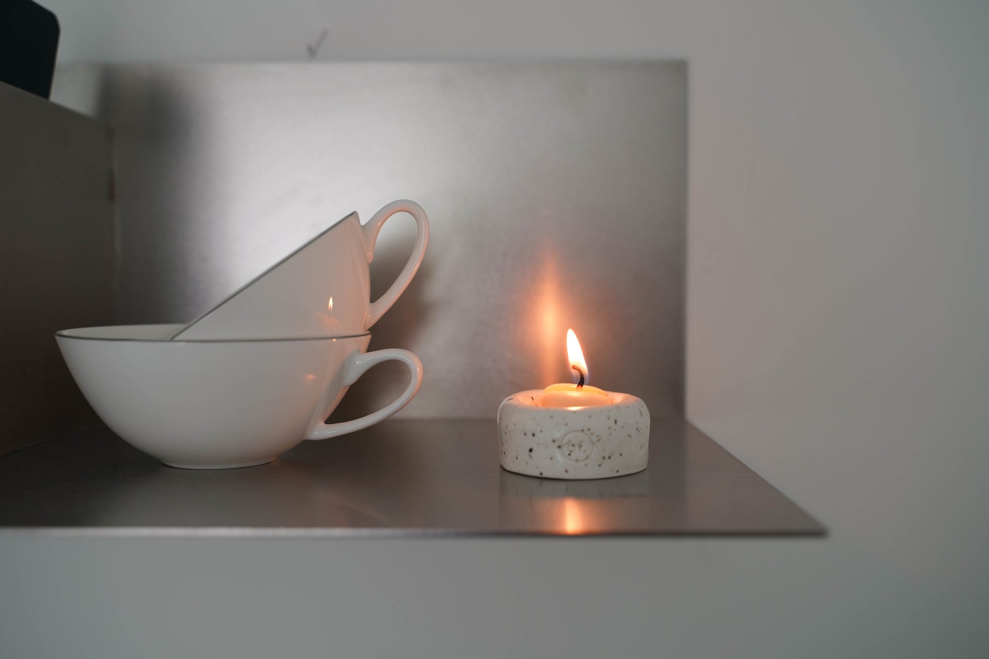 A  small lit Honey Flamingo candle on a metallic surface